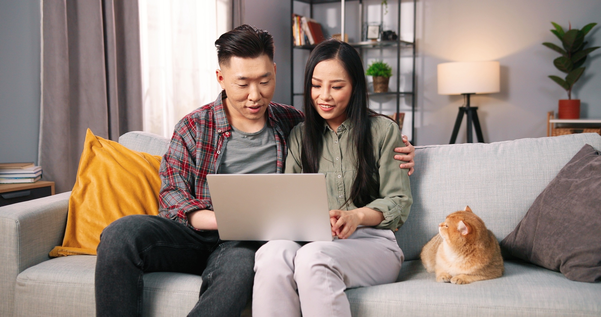 A couple sitting on a sofa with their cat next to them