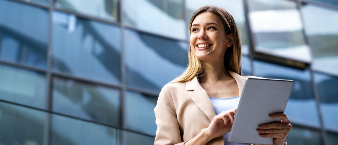 Portrait of smiling woman holding a tablet in urban background