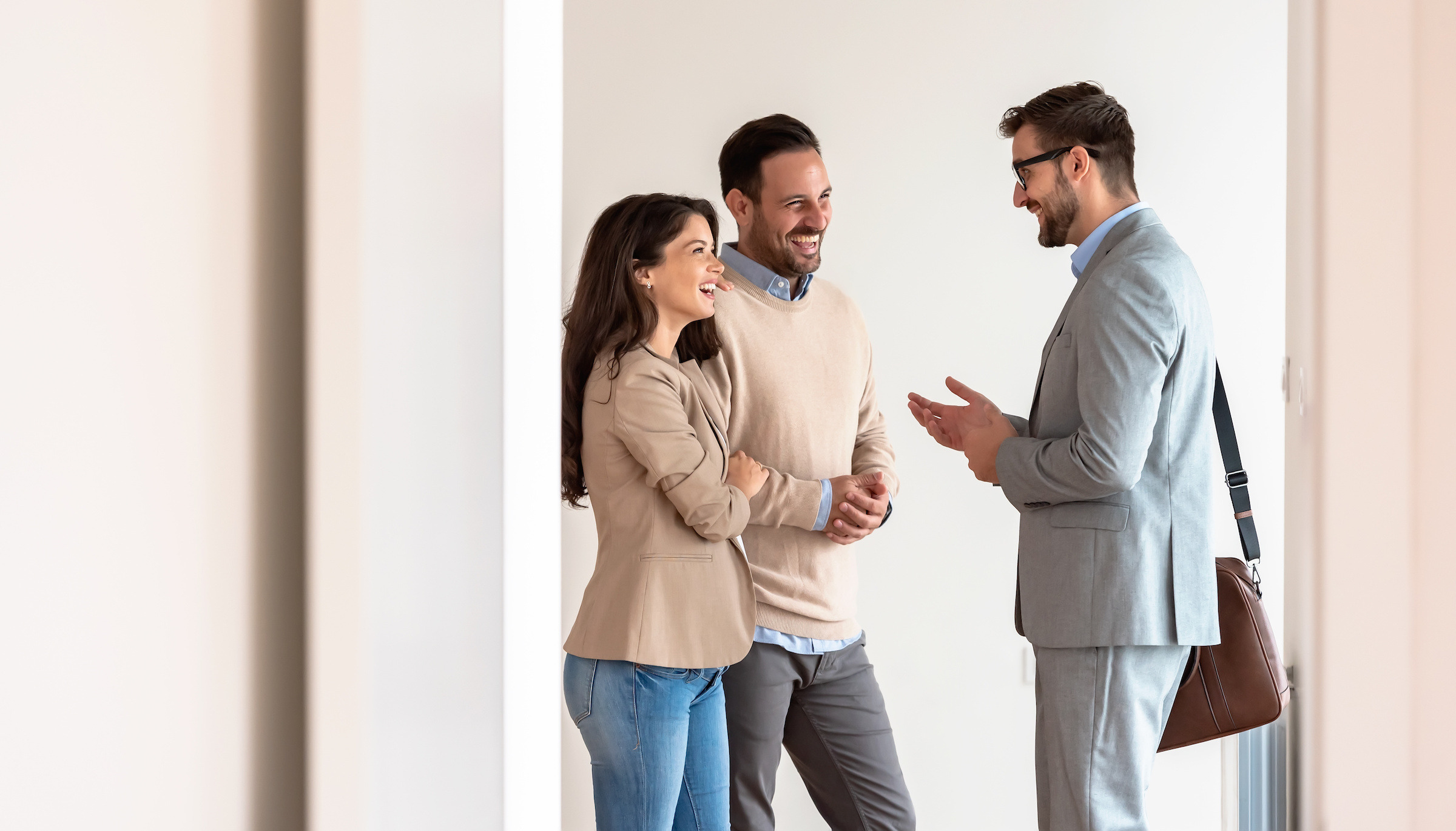 A couple speaking with a broker in an empty room