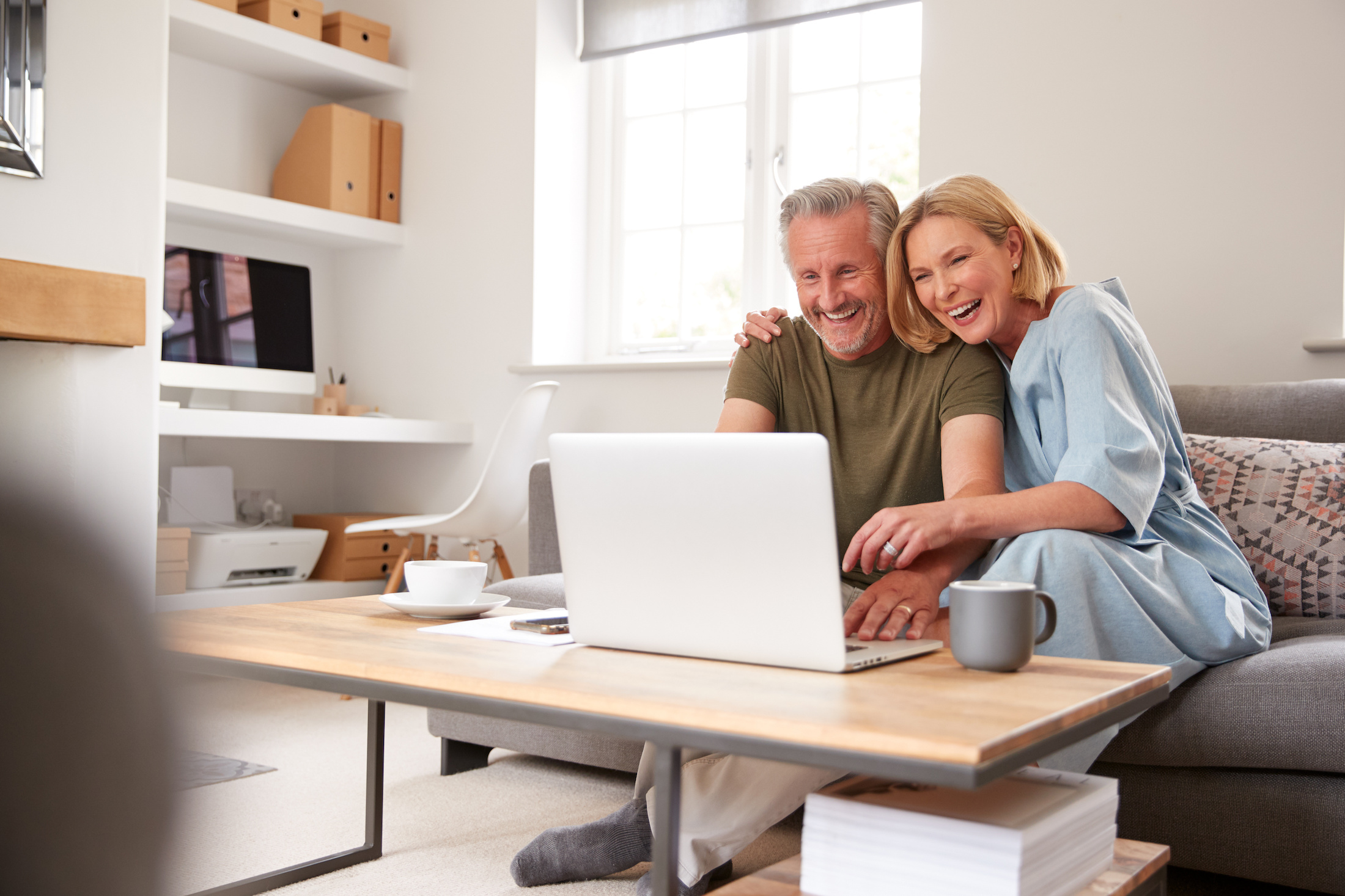 Laughing couple looking at a laptop in a living room