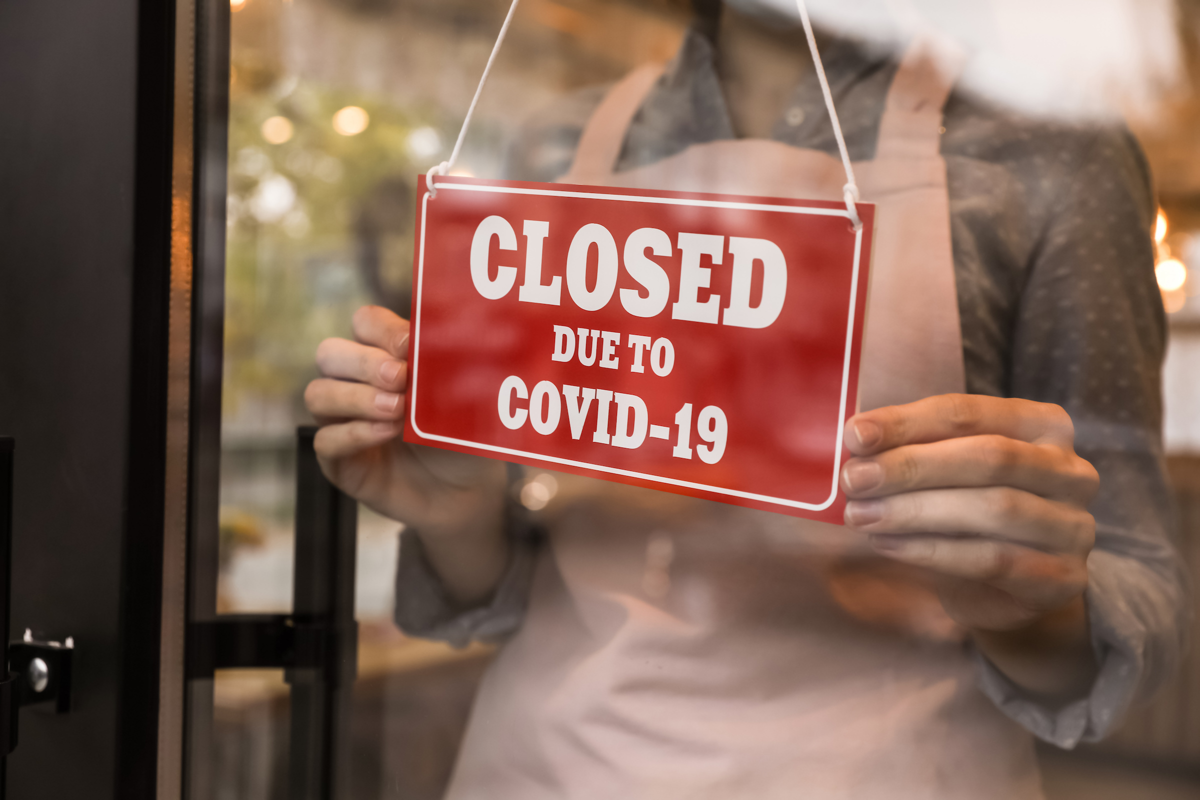 "Closed Due To Covid-19" red sign on a glass door