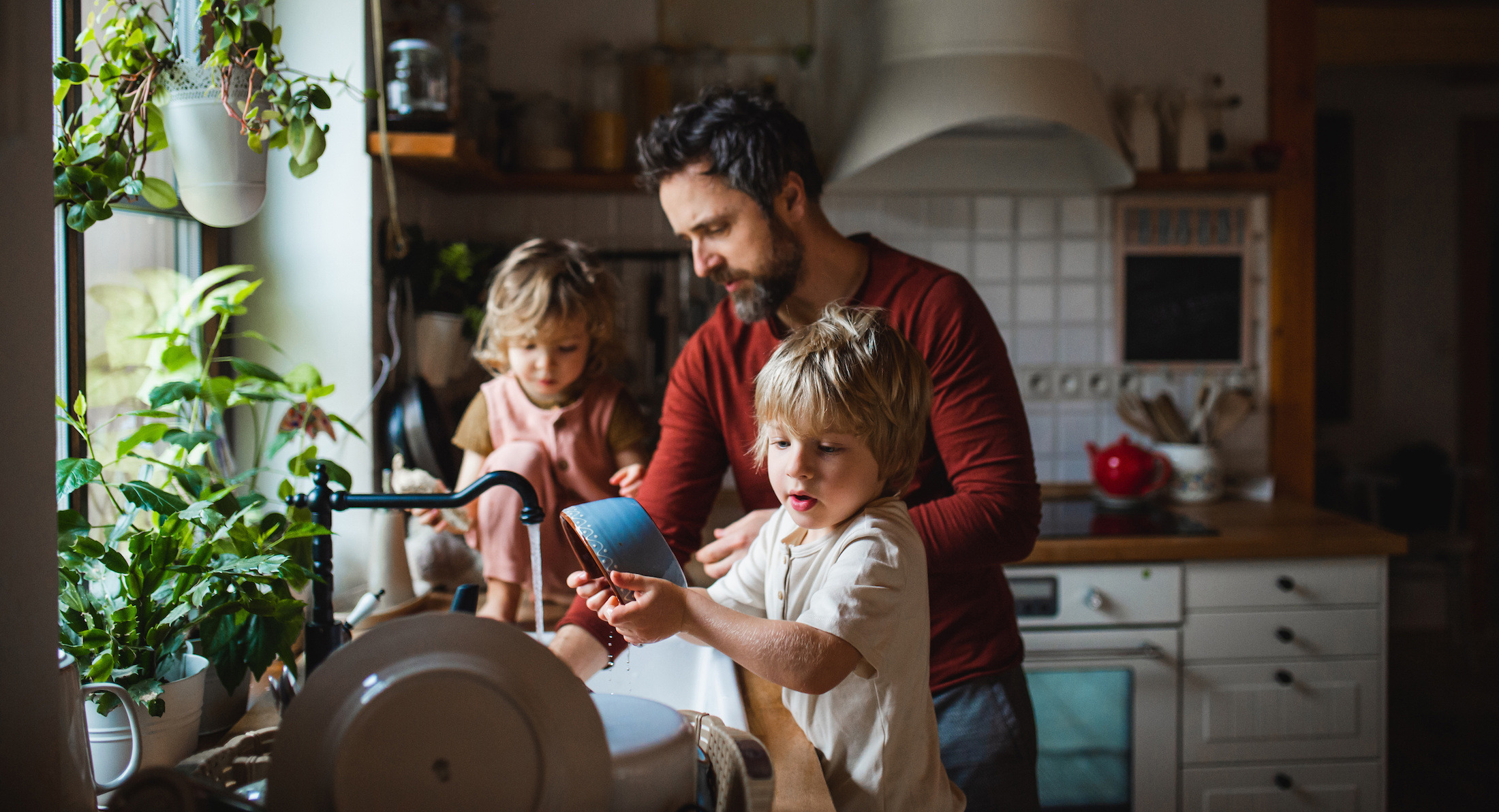 A father washing dishes with his children