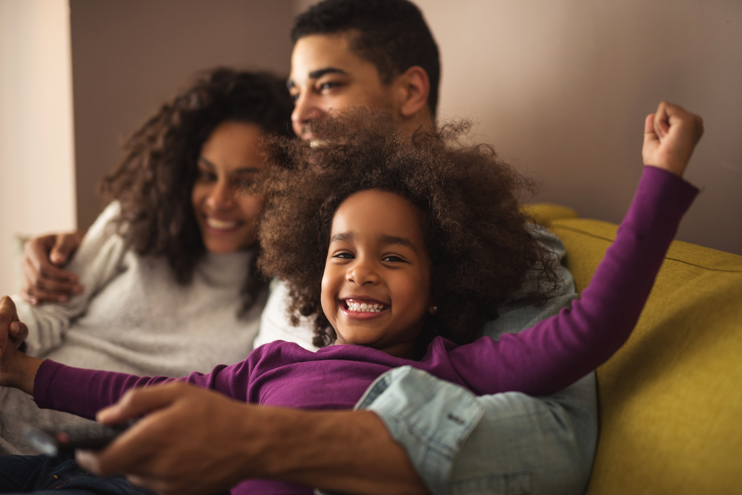 A male sitting on a sofa hugging his wife and child