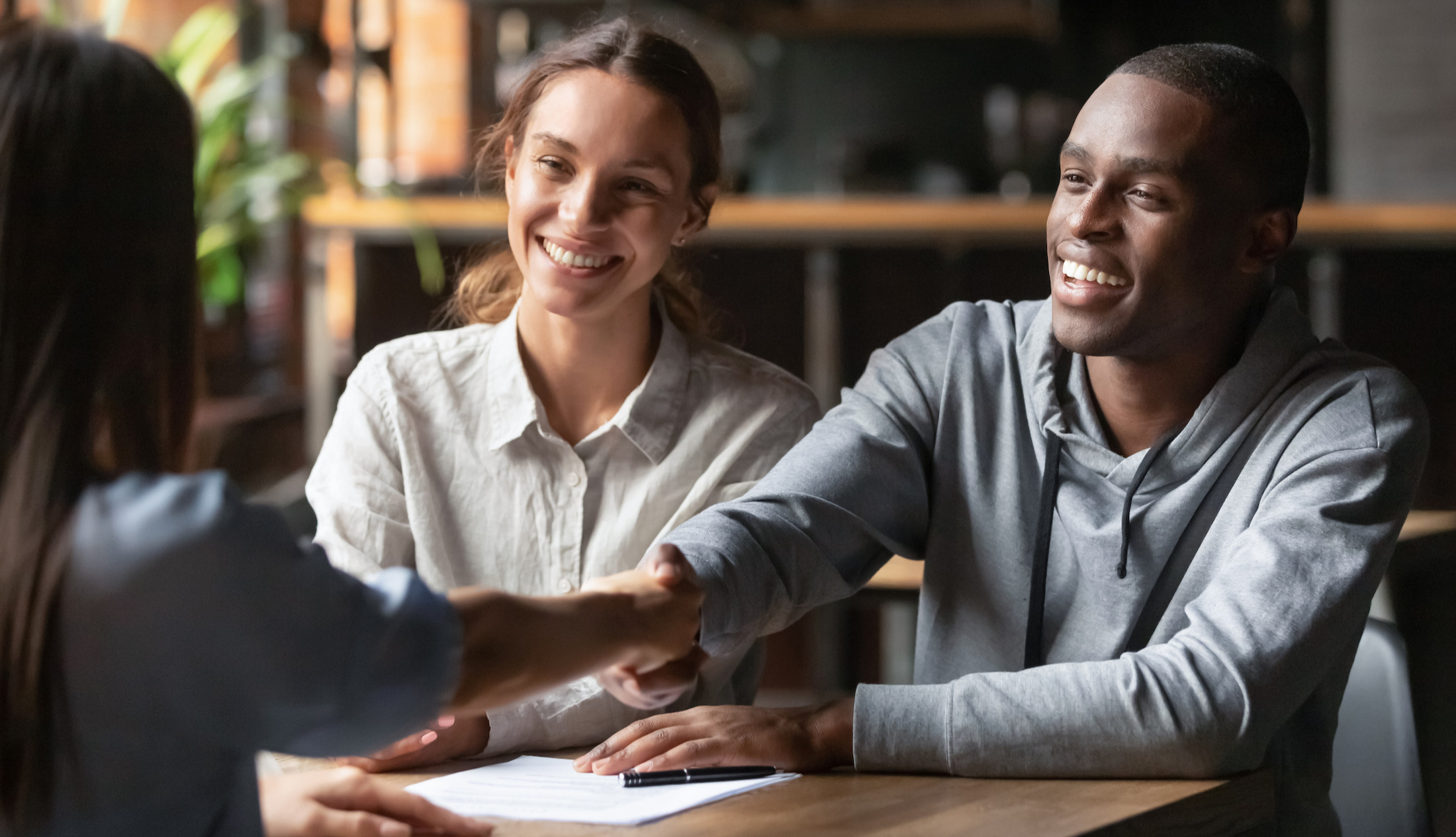 Interracial couple handshaking a broker