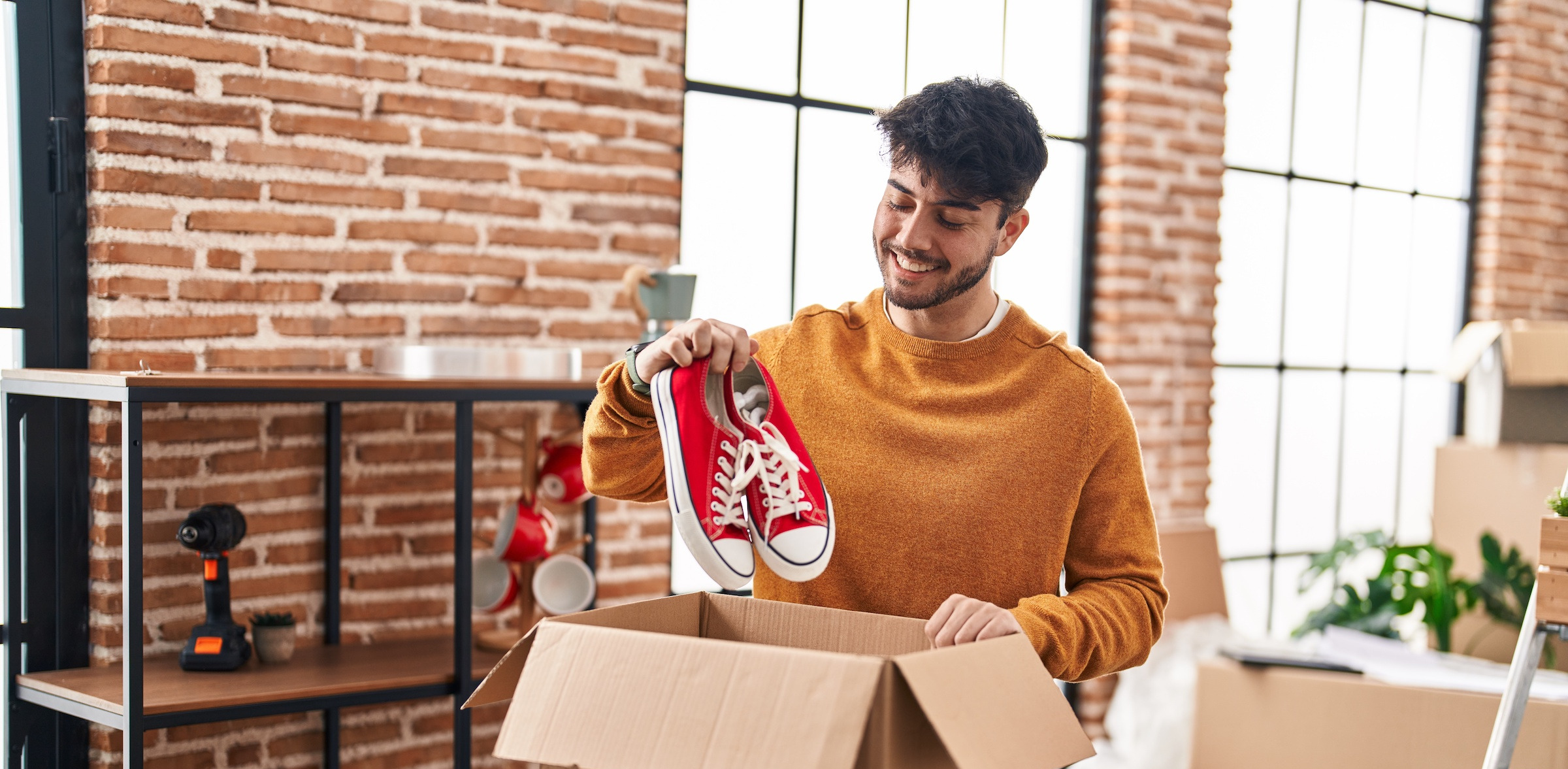 A male holding sneakers unpacking boxes at new home