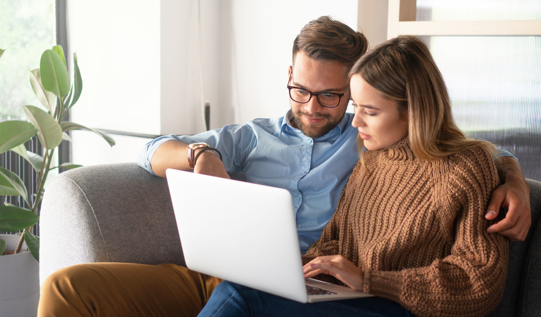 Young couple sitting on a sofa and looking at a laptop