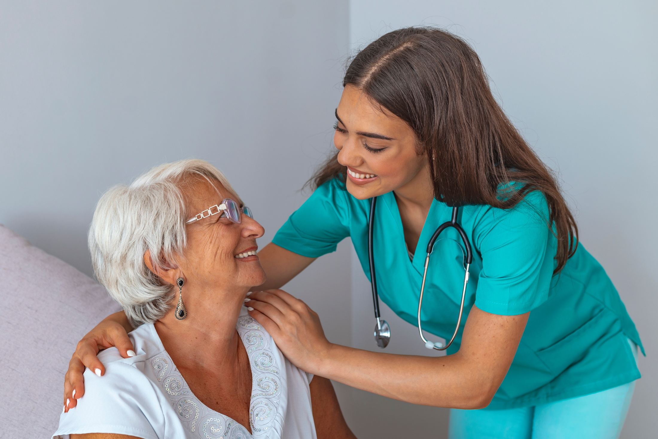A smiling nurse comforting an elderly patient