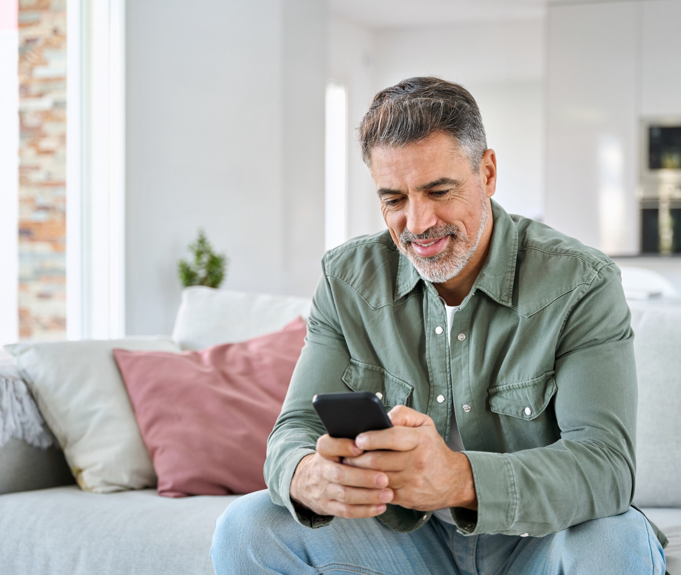 Middle aged man sitting on sofa and using phone