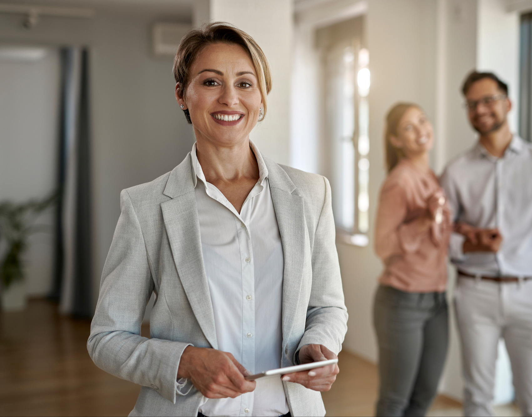 A smiling real estate agent showing a property