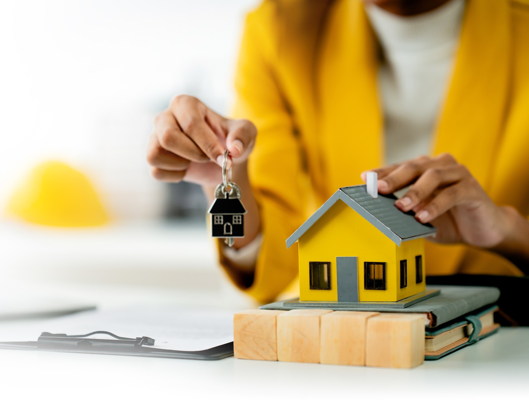 Woman holding keys next to a small model house