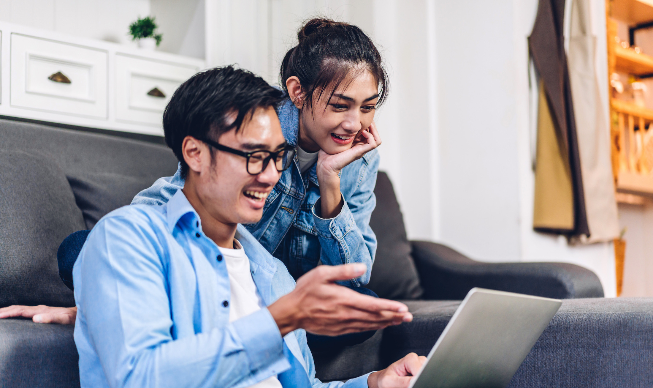 A smiling asian couple looking at a laptop