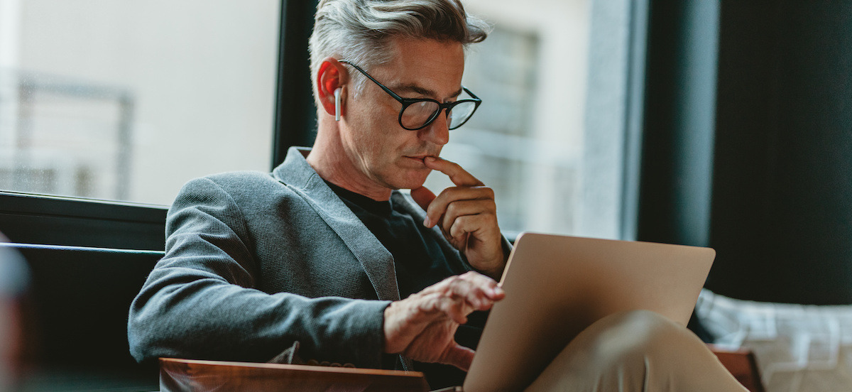 A businessman looking at a laptop in a coffee shop