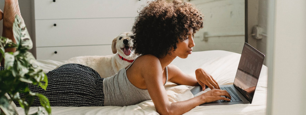 A female typing on a laptop on bed