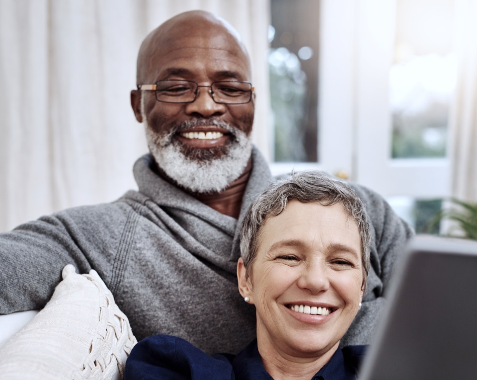 Couple sitting on a sofa and looking at a laptop