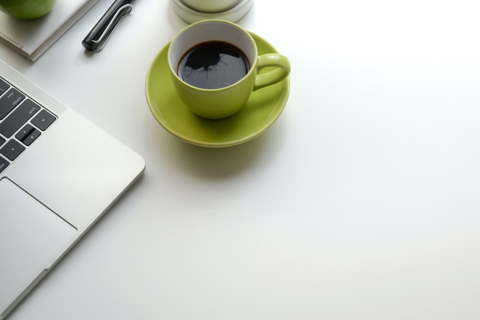 Coffee cup next to a laptop